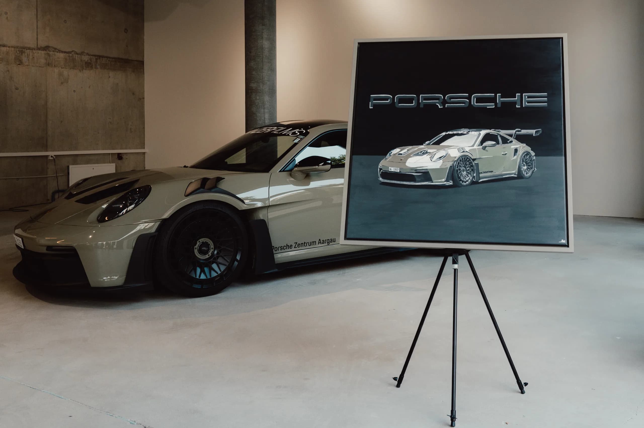 The finished GT3 RS painting on its easel beside the real Porsche 911 GT3 RS